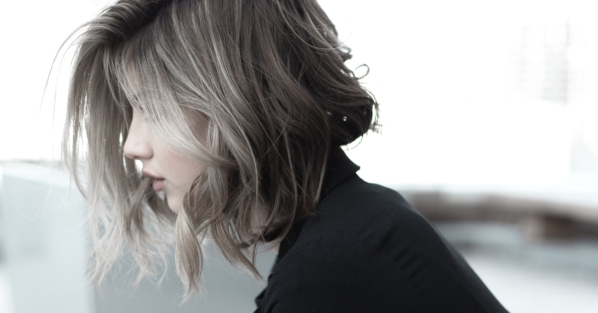 side profile of a young women with short hair that is curled into a beach wave.